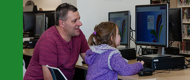 Dad with girl using a library computer